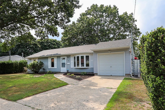 Ranch-style home with a garage, driveway, a front lawn, and roof with shingles