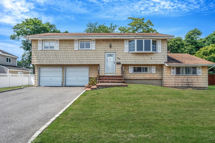 Bi-level home featuring driveway, an attached garage, a shingled roof, and entry steps