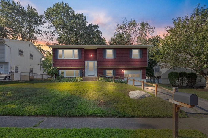 Raised ranch featuring an attached garage and concrete driveway