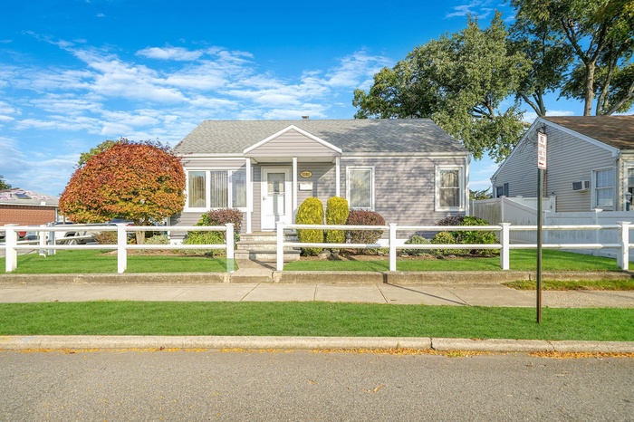 View of front of property featuring a fenced front yard and a shingled roof
