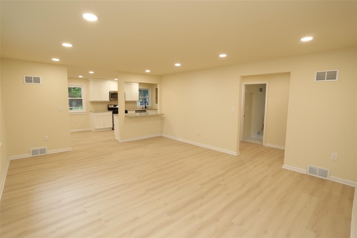 Unfurnished living room with recessed lighting, light wood-type flooring, and baseboards