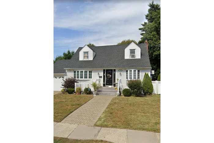 Cape cod-style house with a garage, roof with shingles, and driveway
