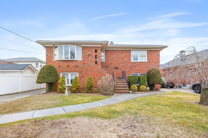 View of front facade featuring brick siding, a front yard, and fence