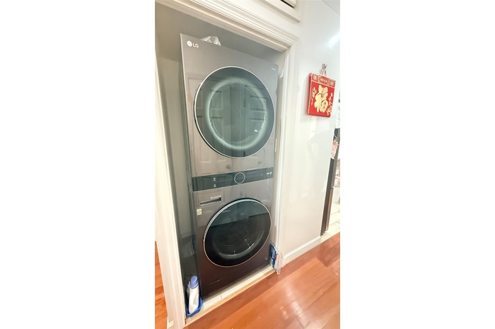 Laundry area featuring stacked washing machine and dryer and wood finished floors