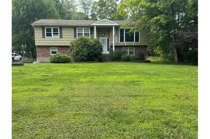 Bi-level home featuring brick siding and a front lawn