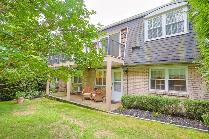 Rear view of property with a balcony, brick siding, and a lawn