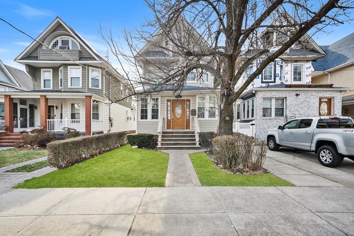 View of front of property featuring covered porch, concrete driveway, and a front yard