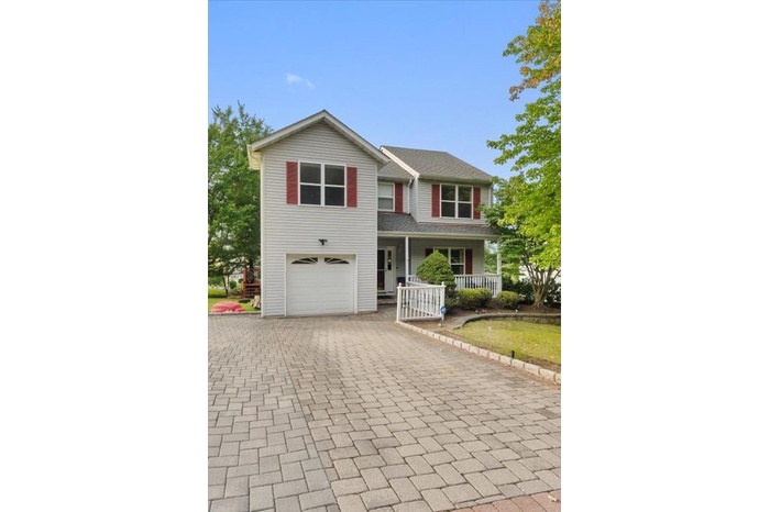 View of front facade featuring covered porch, decorative driveway, and an attached garage
