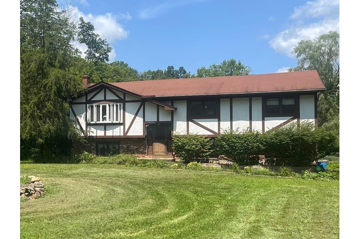View of front of house featuring a front yard, brick siding, stucco siding, and a chimney
