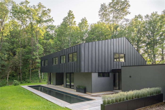Rear view of house with an outdoor pool, board and batten siding, a patio, and stucco siding