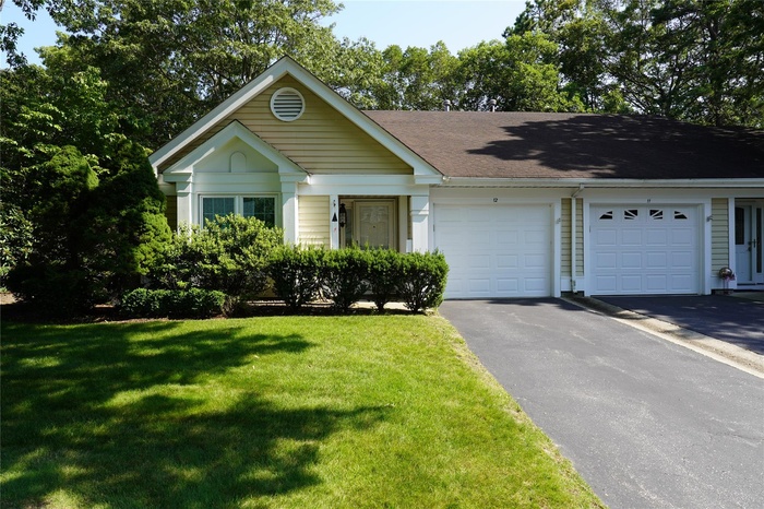 Ranch-style home featuring a garage, driveway, a front lawn, and a shingled roof