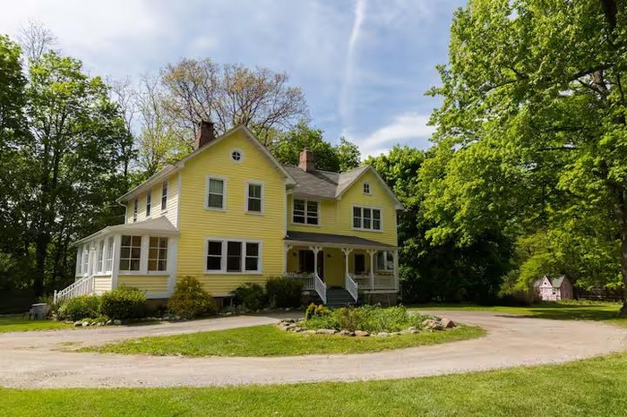 View of front of house with a front lawn, curved driveway, a porch, and a chimney