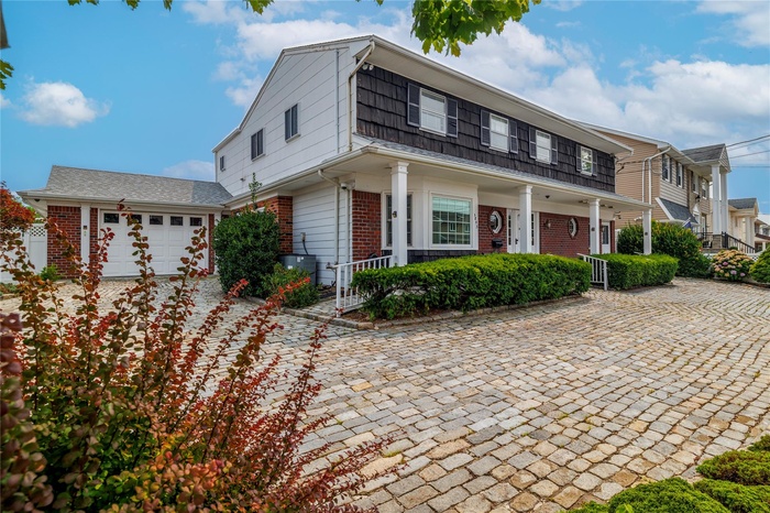View of front of property featuring brick siding, a garage, and a porch