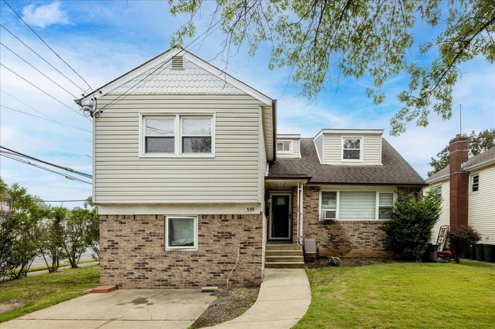 View of front of property with brick siding, a front yard, and a shingled roof