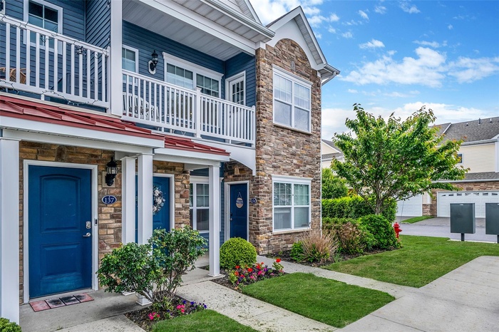 View of front of property with stone siding, a balcony, and a porch
