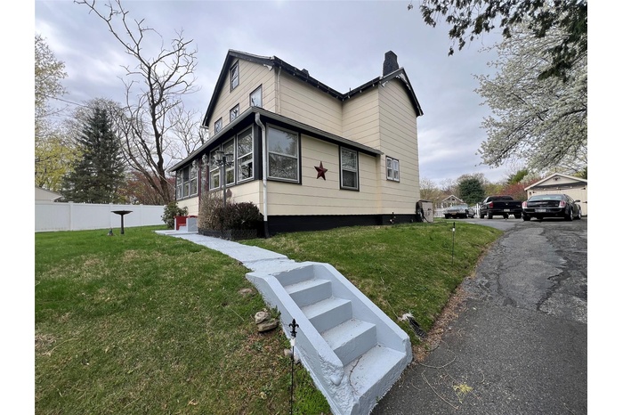 View of property exterior featuring fence, a chimney, and a yard