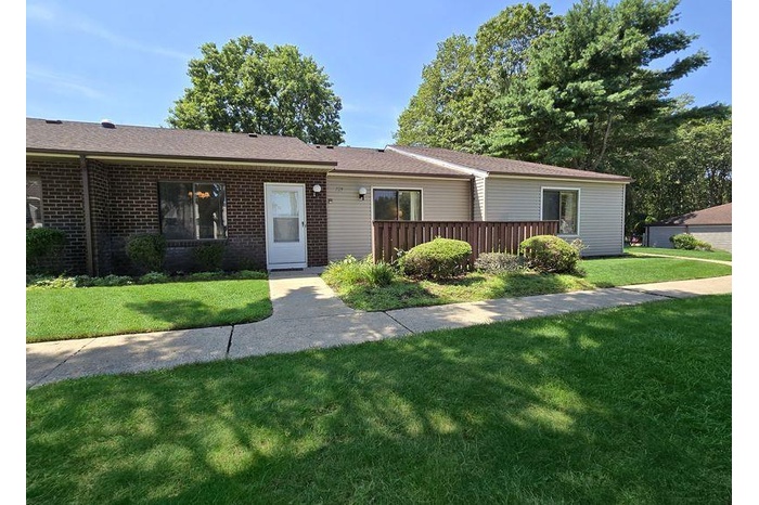 Single story home with a front yard, brick siding, and roof with shingles