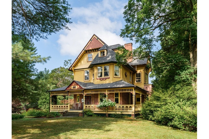 Victorian home with a shingled roof, a front yard, and a chimney