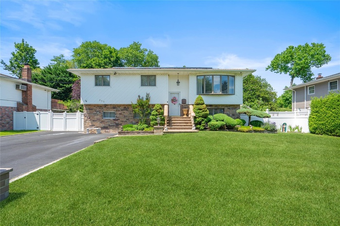Split foyer home with driveway and a wall unit AC