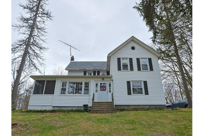 Traditional-style house featuring a chimney, entry steps, a shingled roof, and a front yard