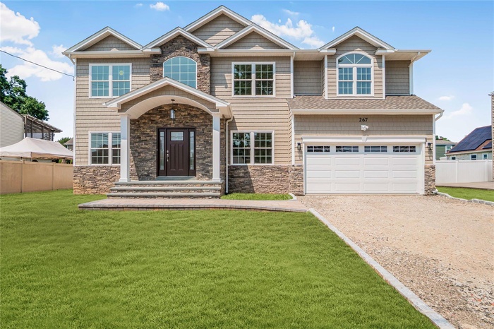Craftsman house featuring dirt driveway, stone siding, and an attached garage