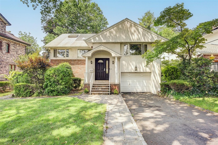 View of front of house with driveway, a garage, a front yard, stucco siding, and brick siding