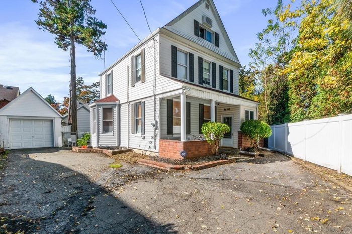 View of front of house with a porch, driveway, an outdoor structure, and a garage