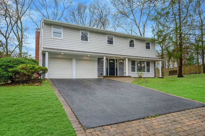 Traditional-style house with asphalt driveway, an attached garage, and a chimney