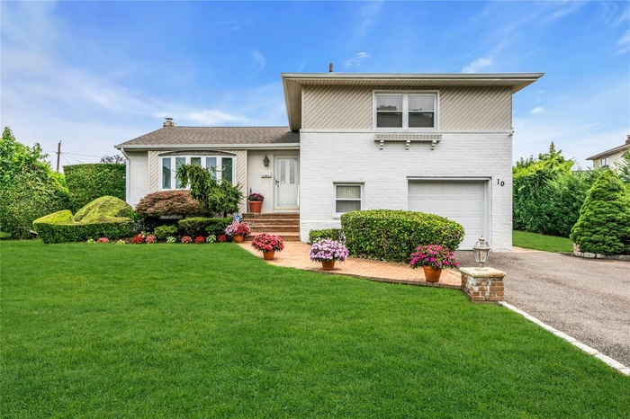 Split level home featuring a garage, driveway, a front lawn, and brick siding