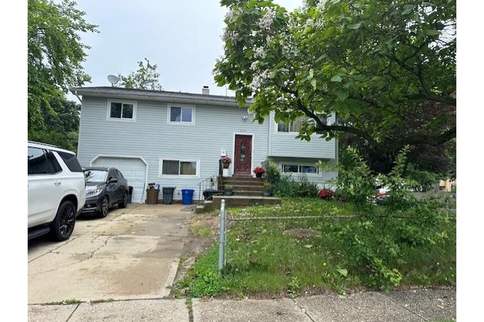 Bi-level home featuring a chimney, an attached garage, and concrete driveway