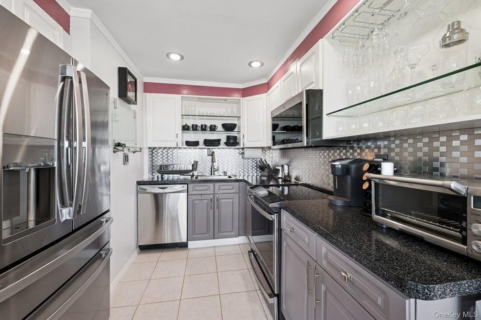 Kitchen featuring stainless steel appliances, crown molding, light tile patterned flooring, gray cabinets, and open shelves