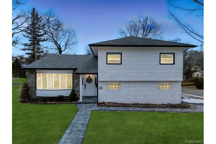 Tri-level home with a front lawn and roof with shingles