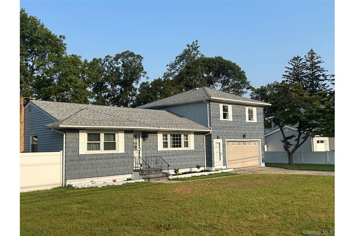 View of front facade with a shingled roof, an attached garage, and driveway