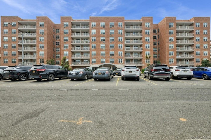 View of apartment building / complex featuring uncovered parking