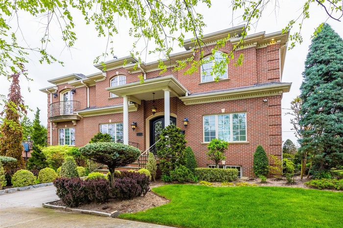 View of front of property featuring a front yard, brick siding, and a balcony