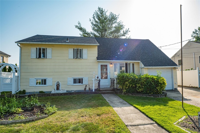 Tri-level home with an attached garage, roof with shingles, and asphalt driveway