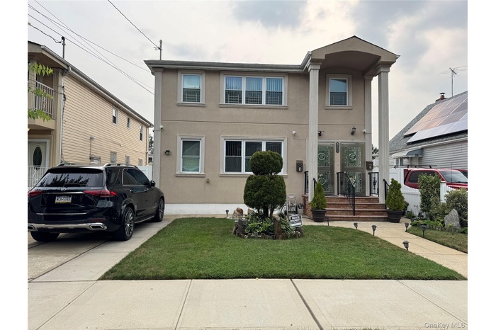 View of front of house with stucco siding and a front lawn