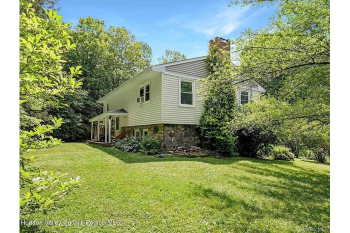 View of home's exterior featuring a chimney, a lawn, and stone siding