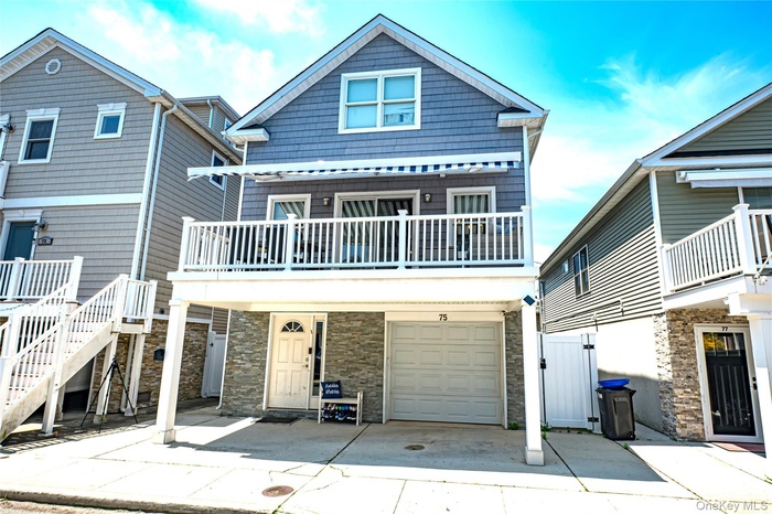 View of front facade with a garage, stone siding, driveway, and a gate