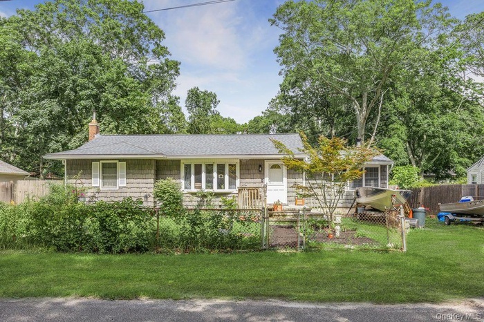 Ranch-style home featuring a fenced front yard, a chimney, and a shingled roof