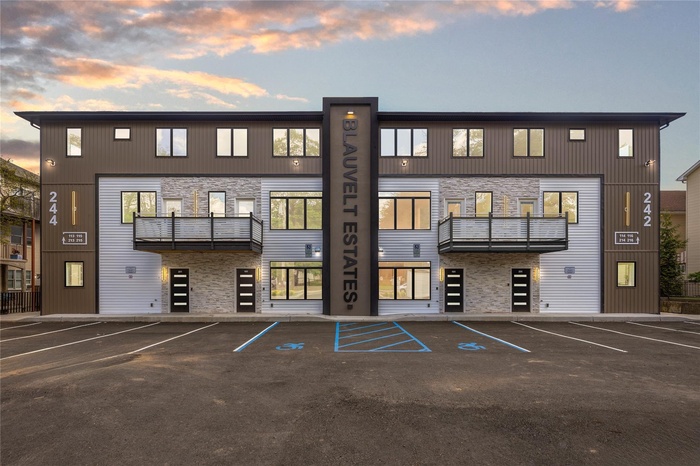 Rear view of property featuring uncovered parking and stone siding