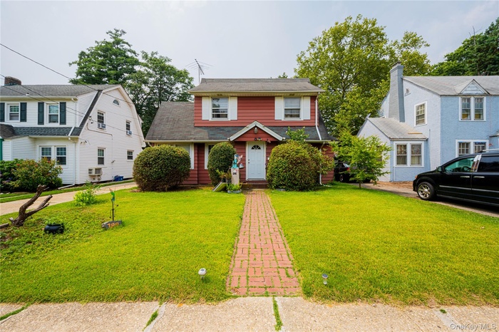 View of front of property with a front lawn and roof with shingles