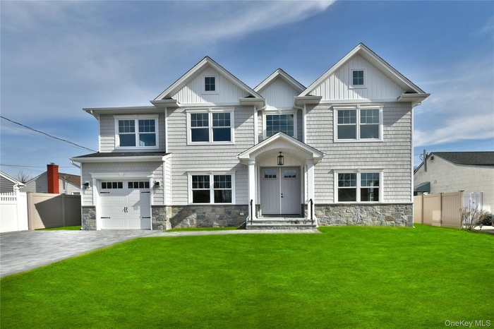 Craftsman-style house featuring stone siding, an attached garage, decorative driveway, and board and batten siding