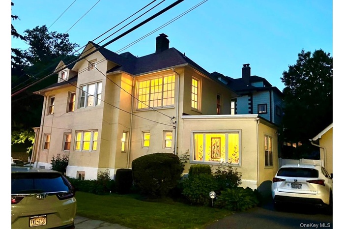 View of front facade featuring a chimney, stucco siding, and a front yard