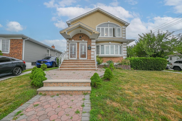 View of front of home with a front yard, stucco siding, and brick siding