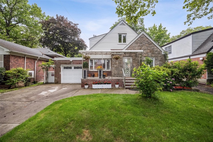 View of front of house featuring an attached garage, a front lawn, driveway, and brick siding