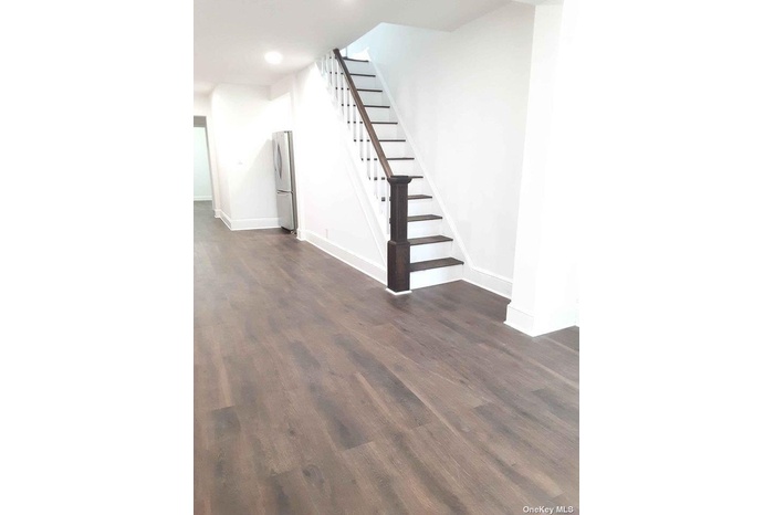 Unfurnished living room featuring stairs, dark wood-style flooring, baseboards, and recessed lighting