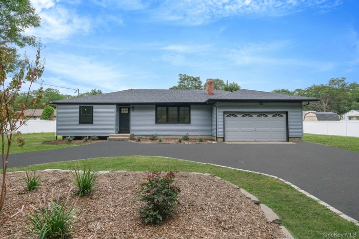 Ranch-style home featuring asphalt driveway, an attached garage, a shingled roof, and a chimney