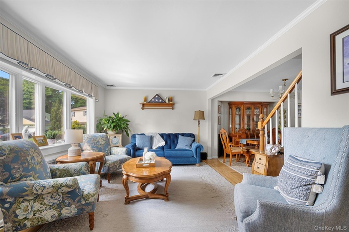Living room with crown molding, light wood-style floors, and stairway