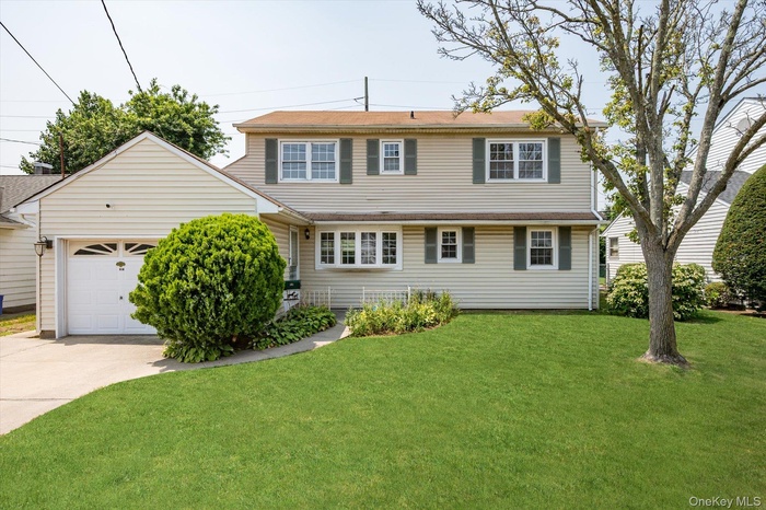 Traditional-style house with a front lawn, concrete driveway, and an attached garage